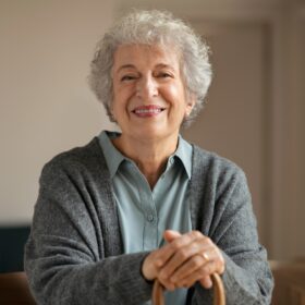 Mujer mayor sonriendo con bastón en casa