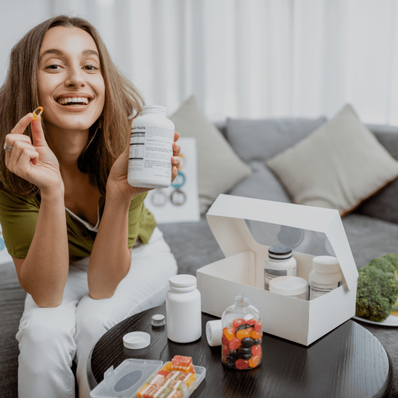 Mujer feliz sosteniendo suplemento y cápsula.