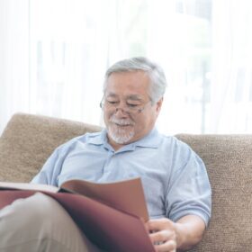 Hombre mayor leyendo un libro en el sofá