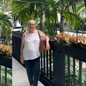 Mujer mayor sonriendo en un jardín tropical